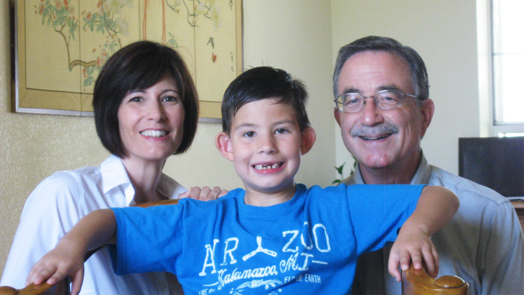 Mom dad and young son with missing front teeth smiling for photo