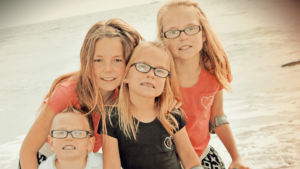 three girls and one boy in family on a beach