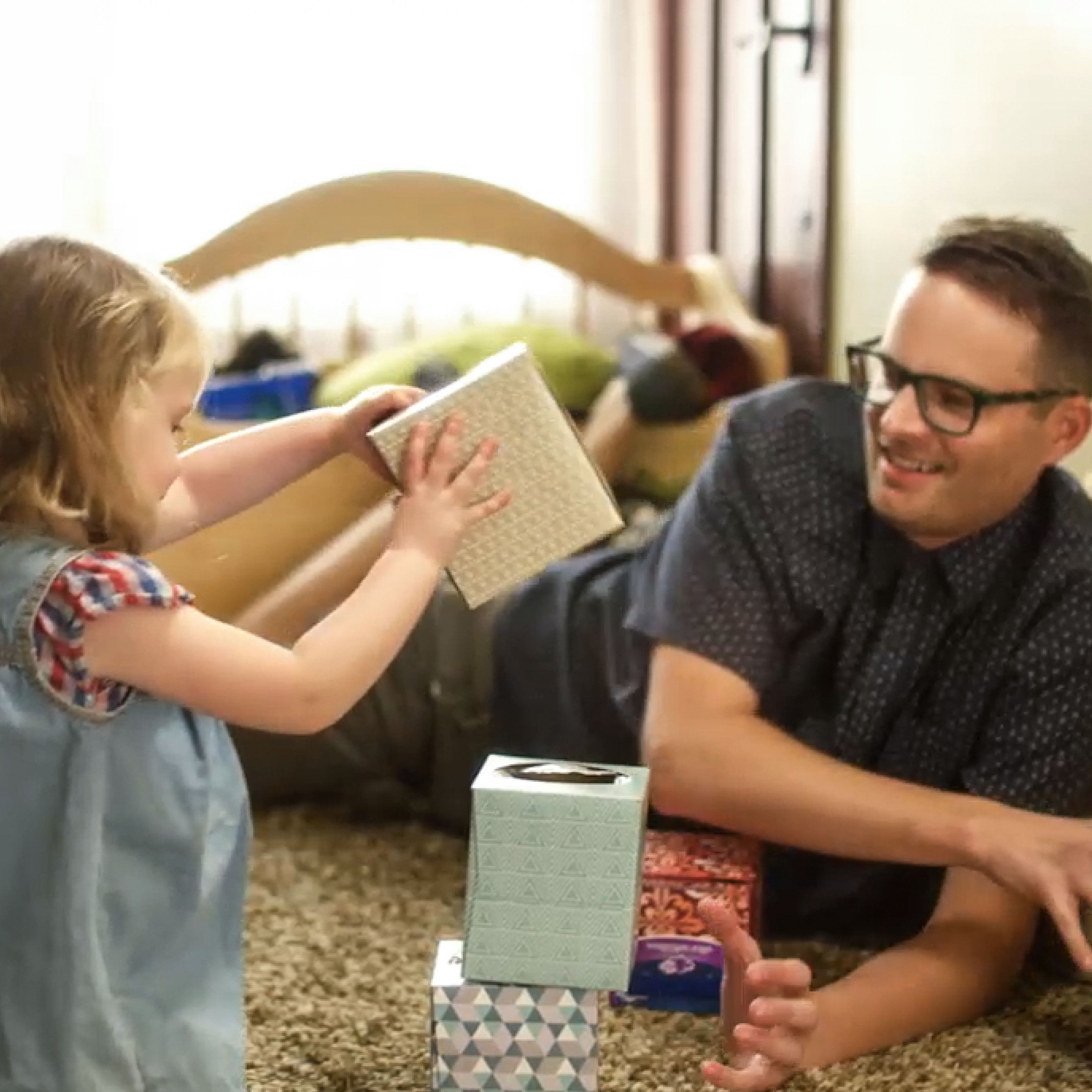 young girl playing with dad and tissue boxes