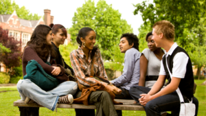 A group of young adults sitting on a bench outside