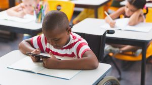 Young African-American boy in wheelchair at a desk in a classroom