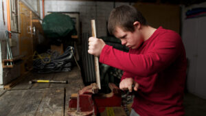 Teenager with Down syndrome placing wood in a vice in a workshop