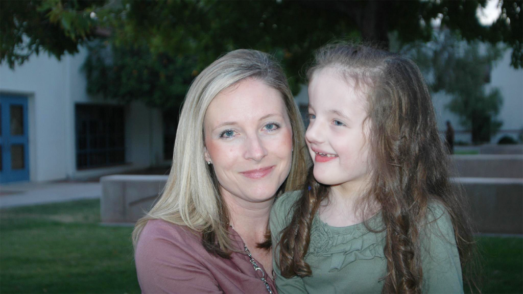 Blonde mom next to young daughter with long curly hair