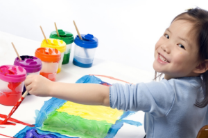 preschool girl painting with multiple colors