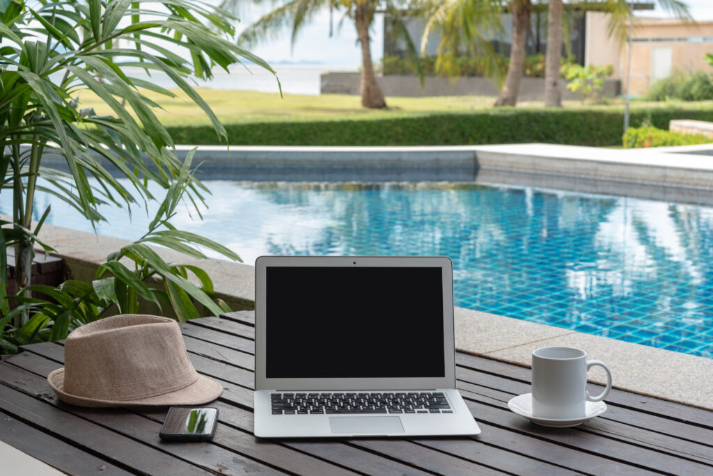 laptop and coffee cup on a table next to a pool