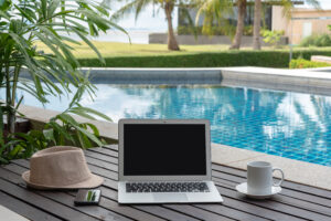 laptop and coffee cup on a table next to a pool