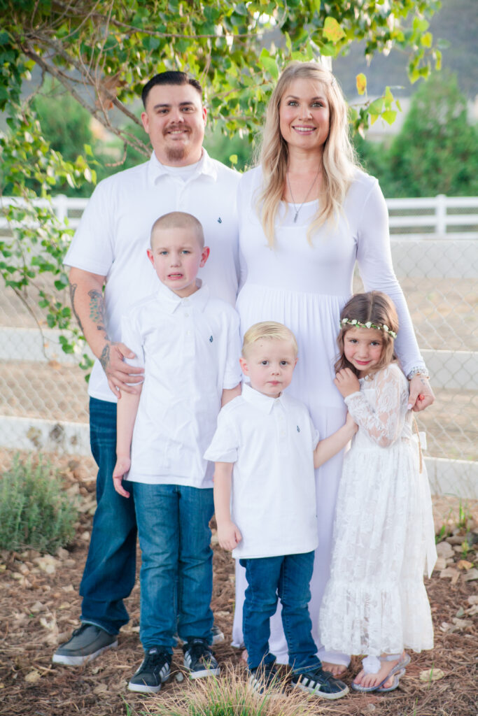 family with father and mother with two young sons and a daughter all wearing white.