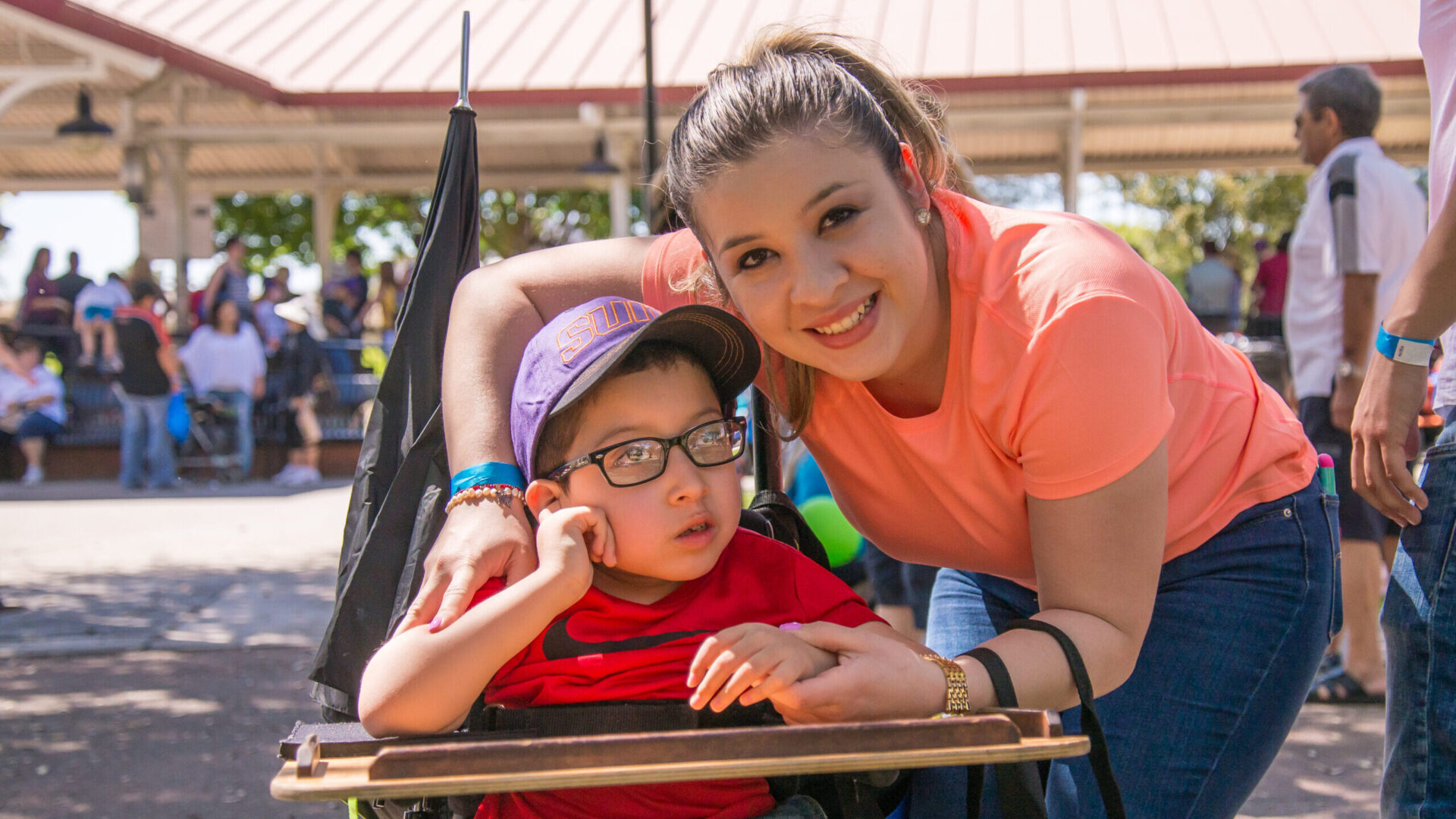 young mom with arm around son who is in a wheelchair