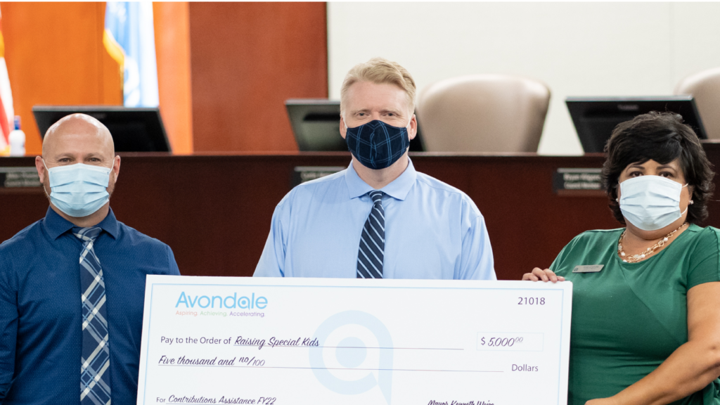 Three adults holding large donation check for Raising Special Kids