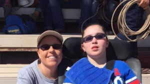 Smiling mom squatting next to daughter in wheelchair