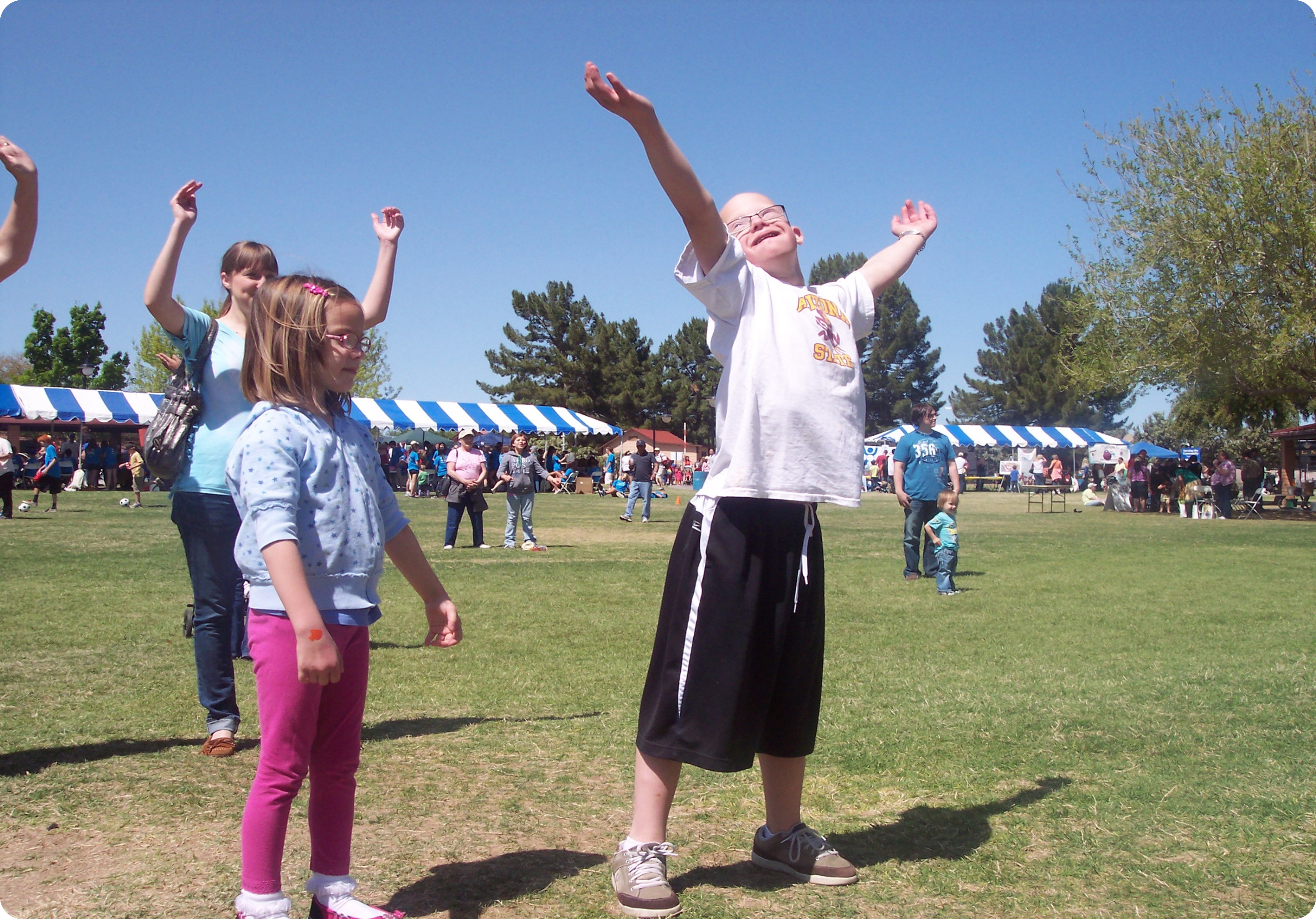 young man with Down syndrome with arms lifted and smiling at the sky