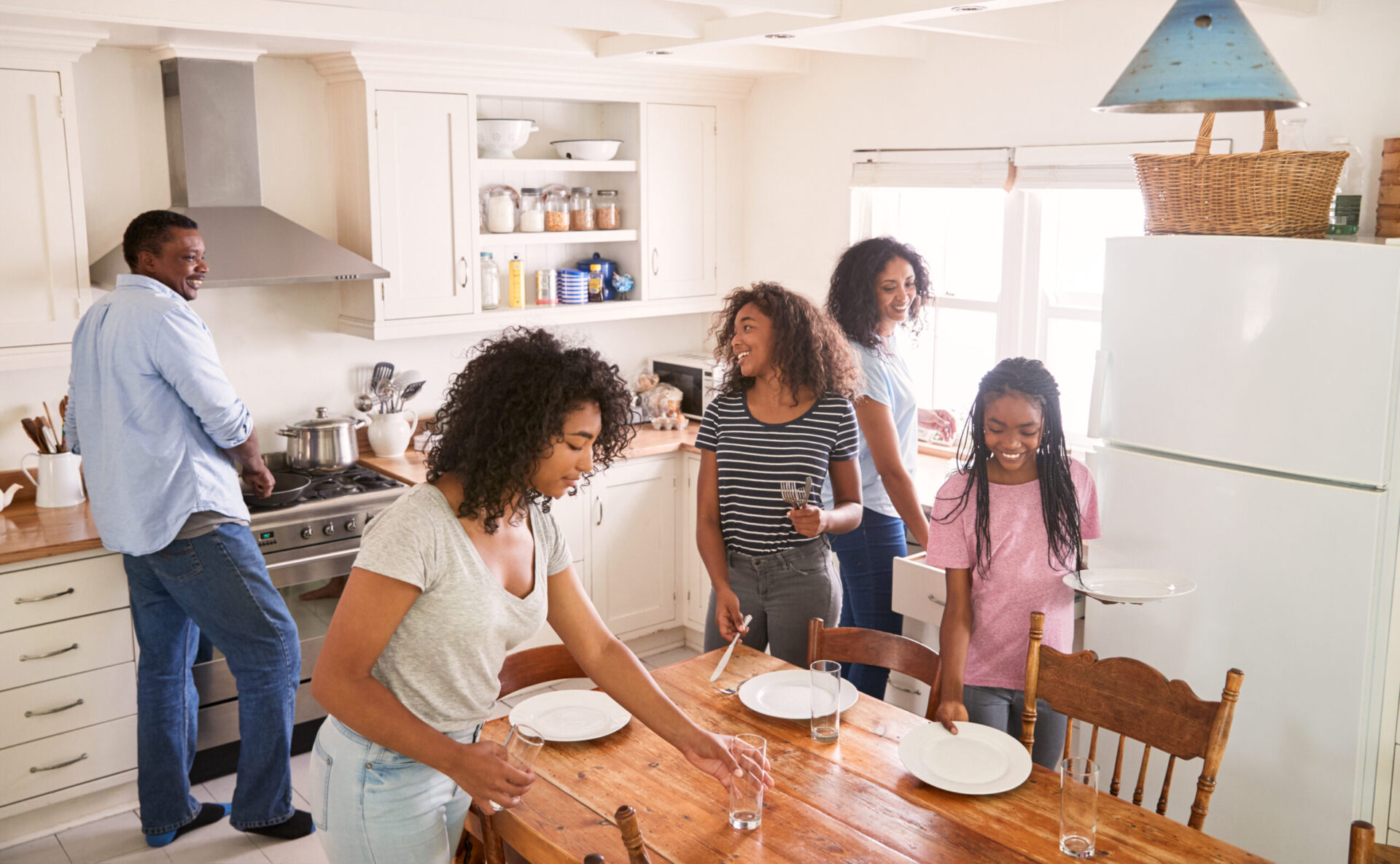 familly in a kitchen all helping one another set the table