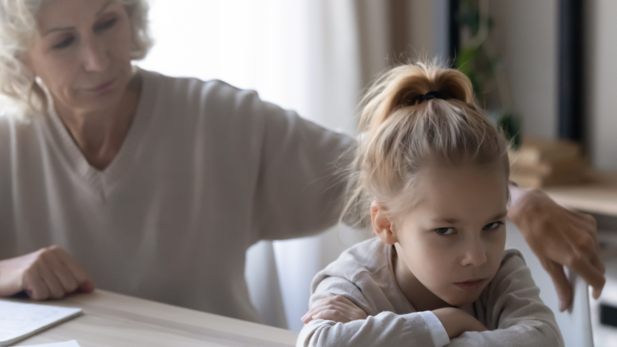 young girl with a defiant look on her face with her back to a woman