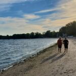 two figures walking away from the cameral down a beach at sunset.