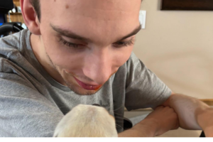 Young man sitting in his wheelchair looking down at his dog